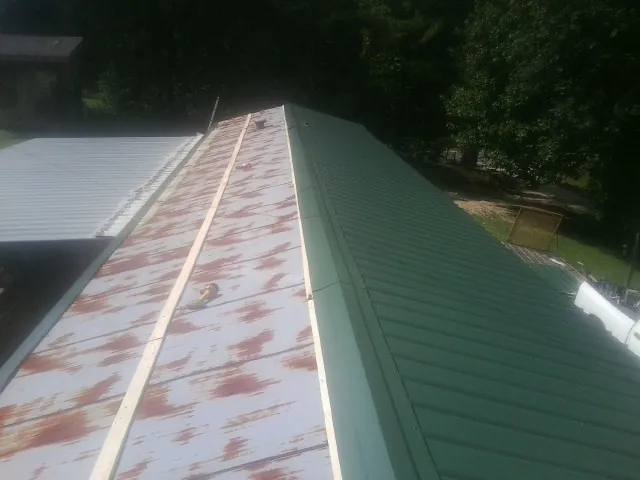 Old rusted panels beside newly installed green metal roofing — Wind Damage Roof Repair by Roofing Brothers in Dearing