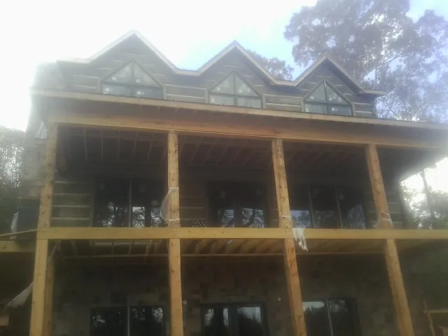 Dormers and porch framing on a large log home under construction — Roof Coating work by our crew in Dearing