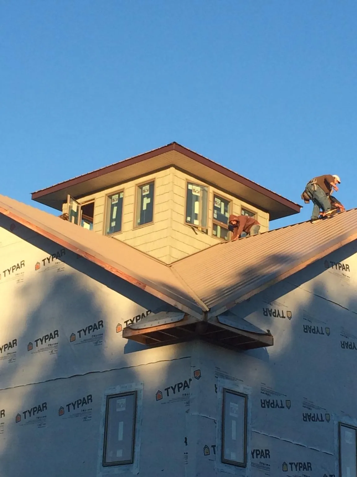 Roofers working around a rooftop cupola on a new metal roof at sunset — Roof Waterproofing in Dearing by Roofing Brothers